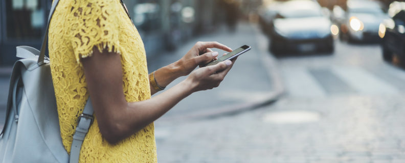 Tjej går i gatan med telefon